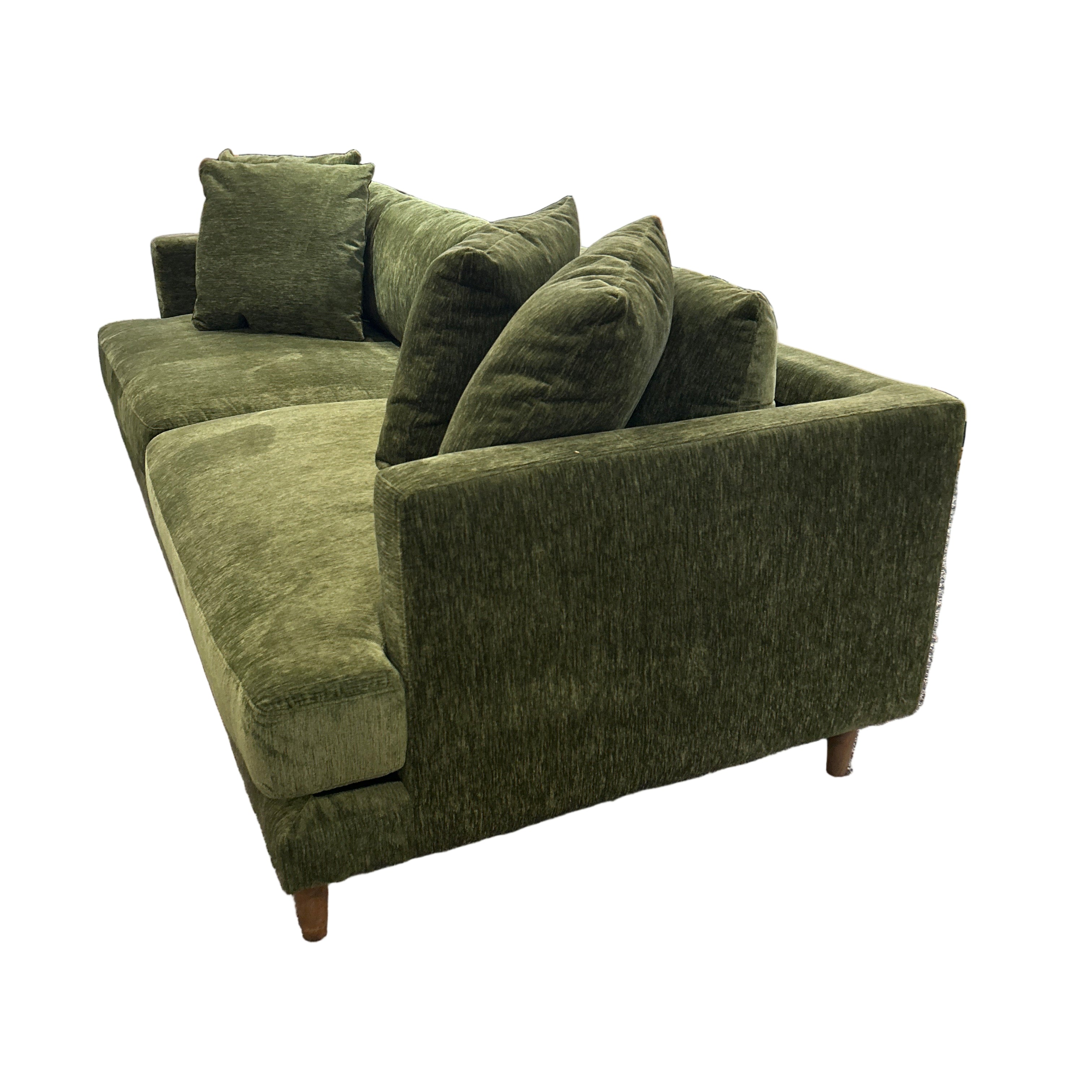 Green upholstered chair in a store setting with shelves and products in the background