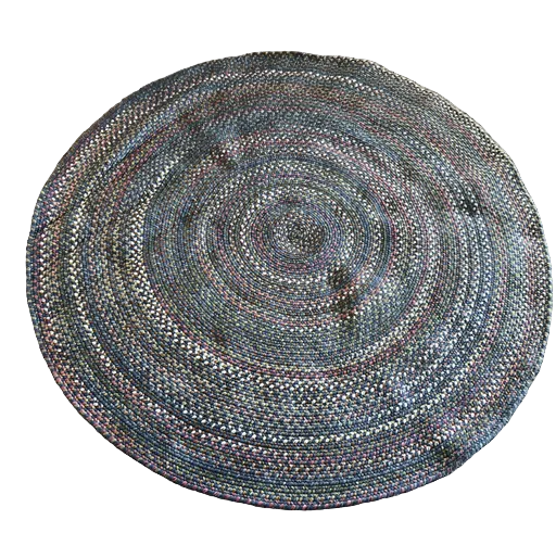 A colorful, braided round rug with concentric circles lies on a soft, light gray carpet, adding texture and warmth to the space.