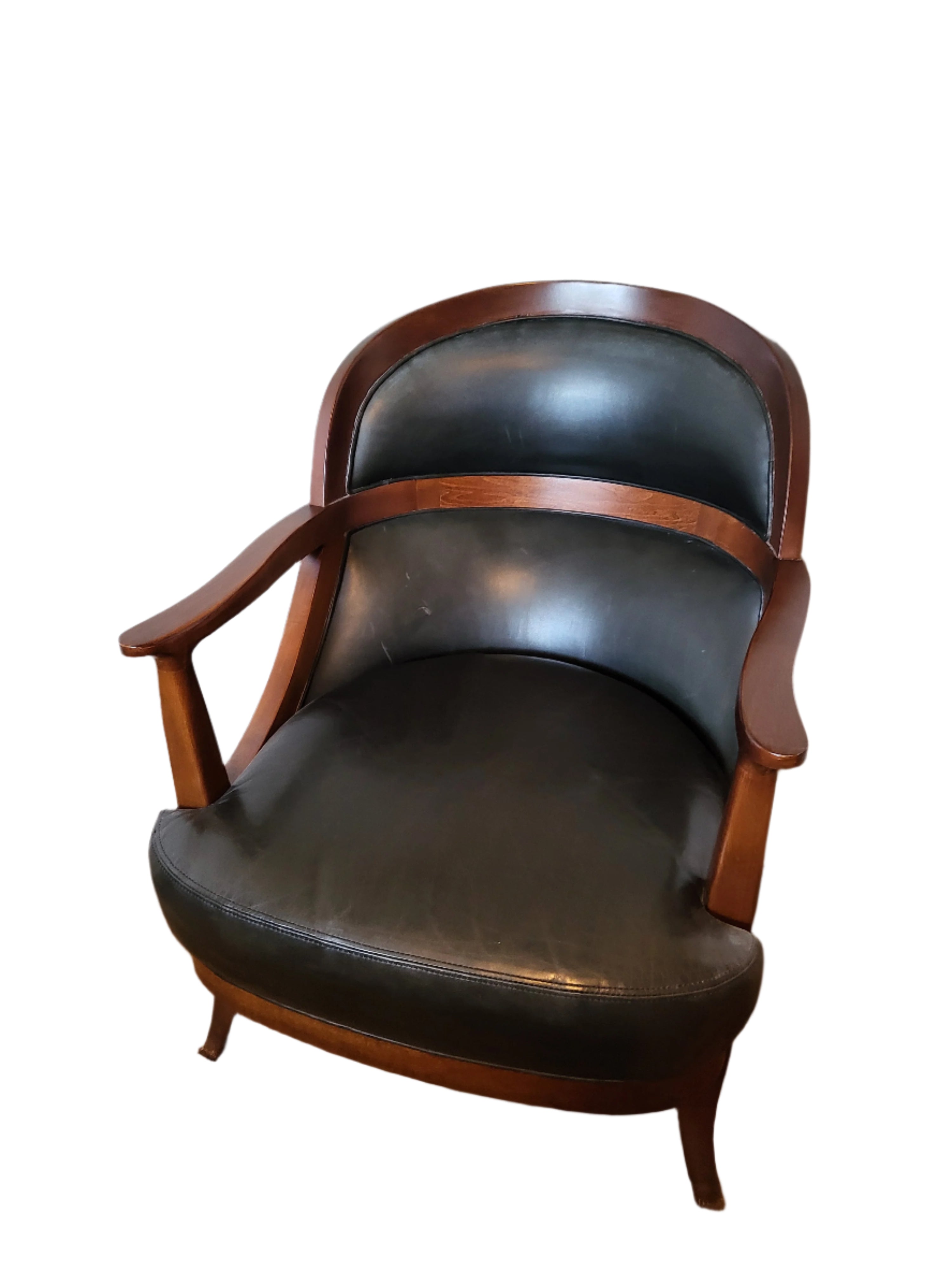 A vintage wooden armchair with a black leather seat and backrest, positioned against a light-colored wall on a beige carpeted floor.