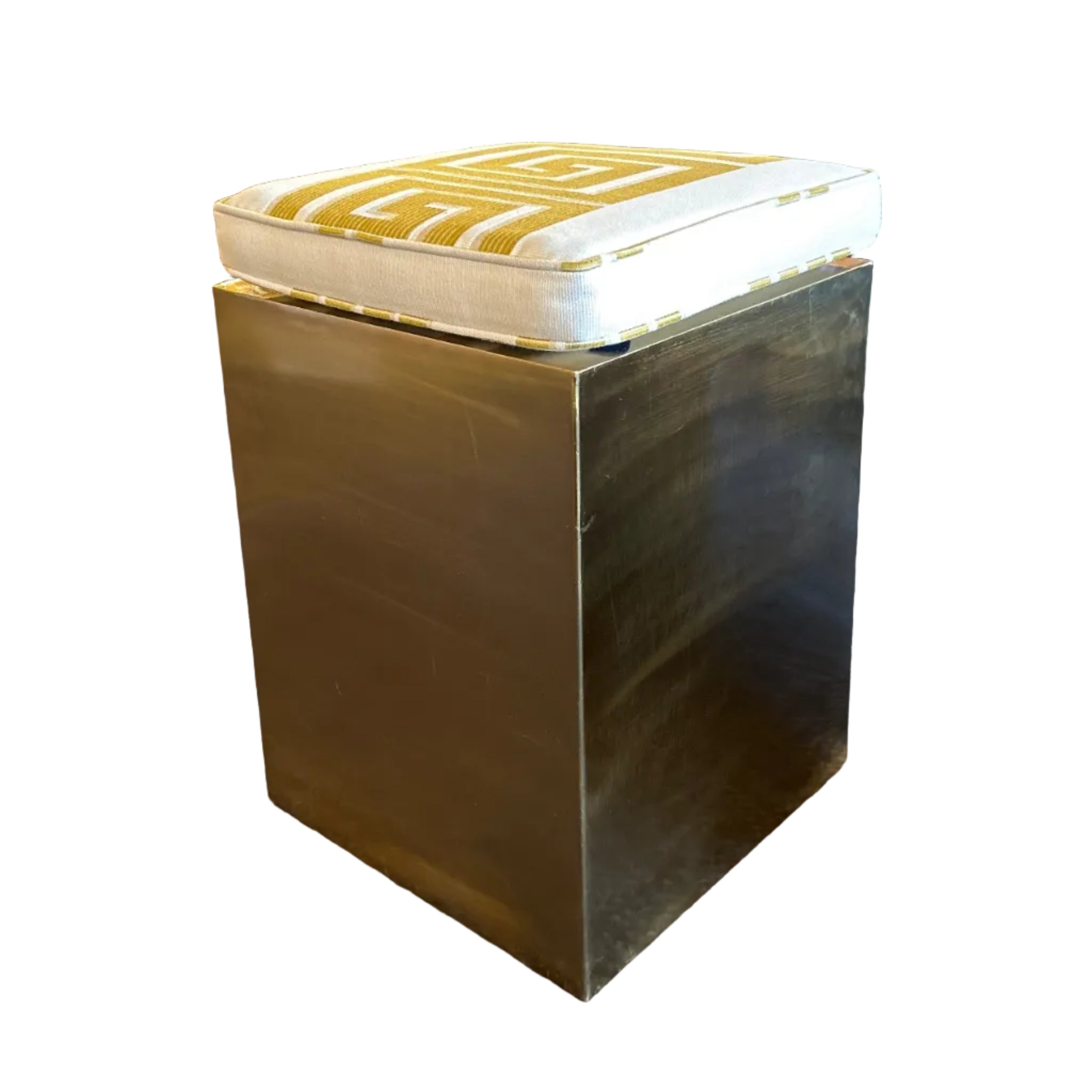 Gold cube-shaped stool with a patterned cushion on a white background