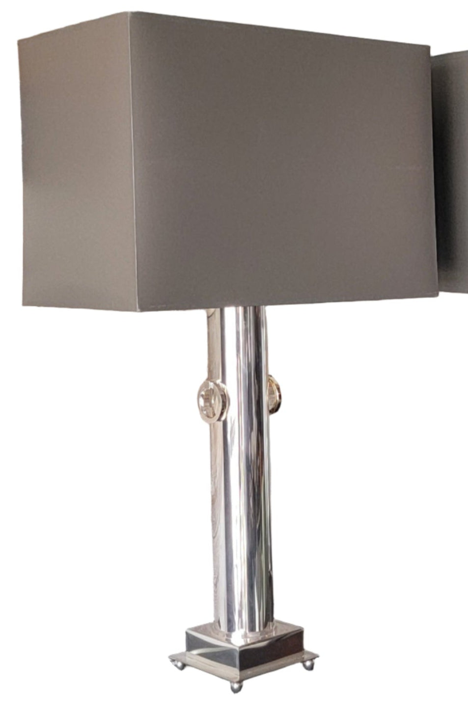 Two modern lamps with rectangular gray shades on a black countertop against a rustic wooden wall. Simple and stylish design for contemporary decor.