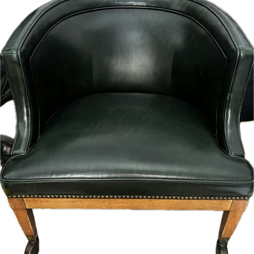 A vintage green leather armchair with a curved back and wooden legs, featuring decorative nailhead trim along the base for added elegance.