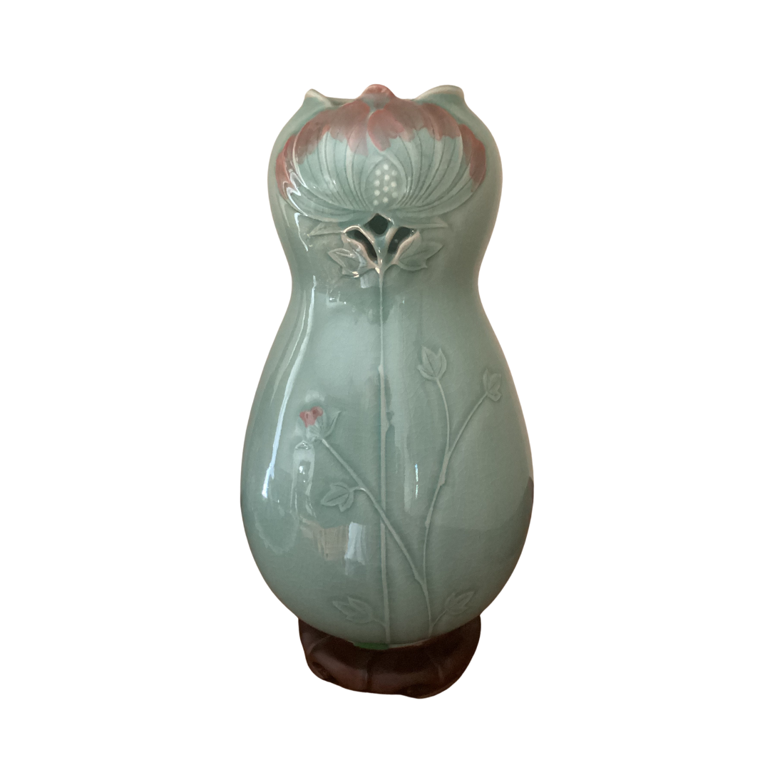 A decorative, light blue vase with a floral design. It features a flower opening at the top and leaf motifs along the body for an elegant touch.