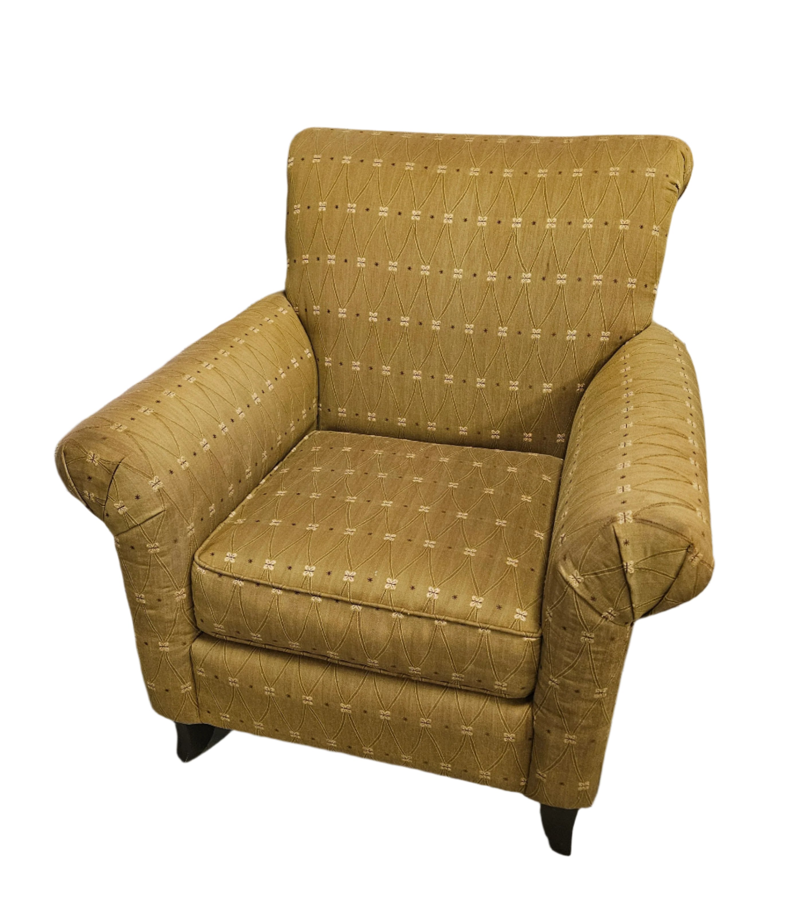 A light brown armchair with patterned upholstery sits in a room with wooden flooring and a black-framed mirror reflecting the surroundings.