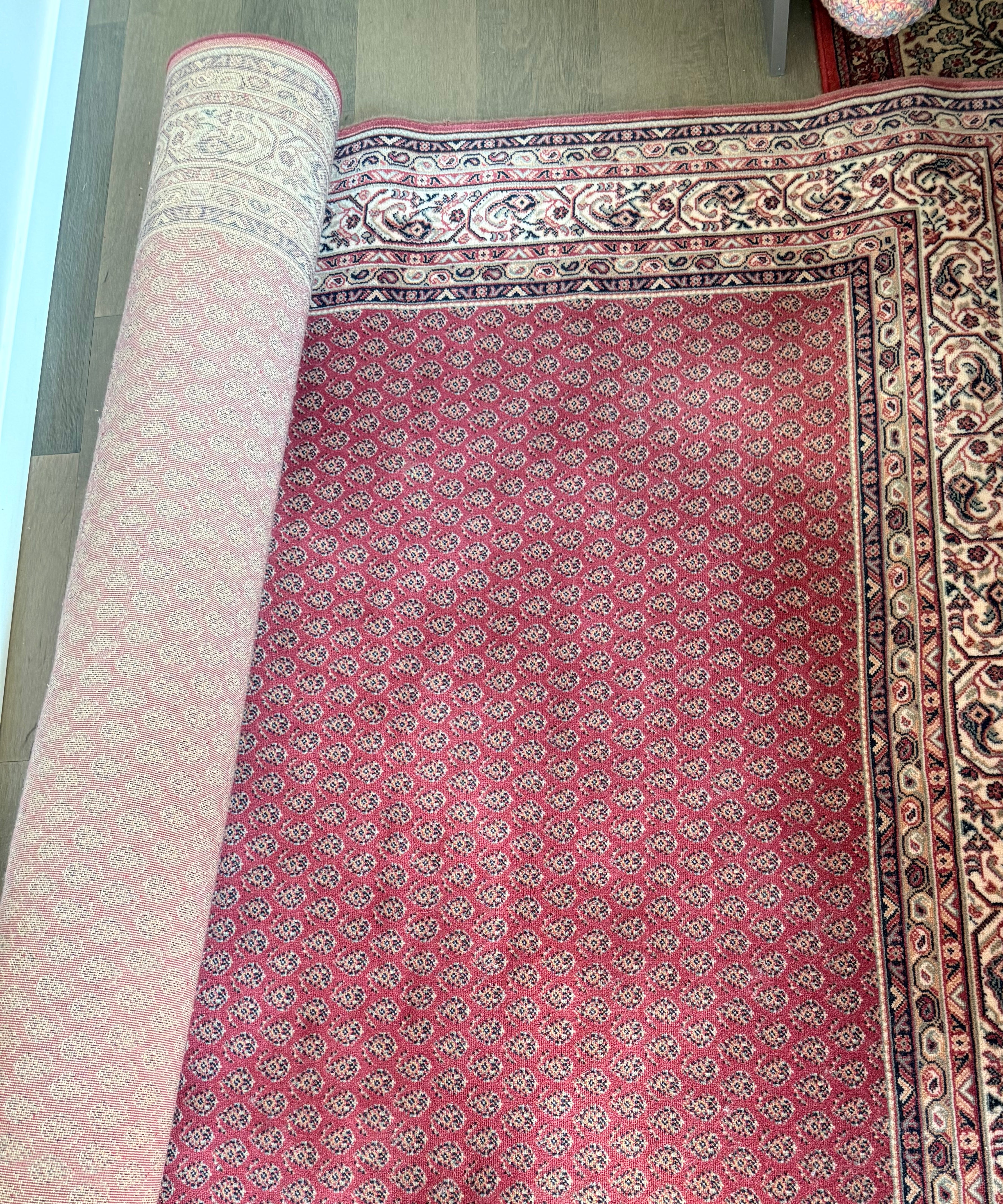 A patterned red carpet is partially rolled out, showcasing detailed motifs in its border. The wooden floor adds warmth to the setting.