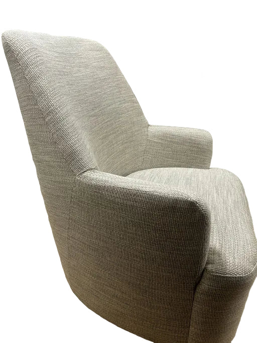 A light gray, textured armchair is positioned at an angle. Behind it is a closed door painted in muted tones, adding a cozy feel to the room.