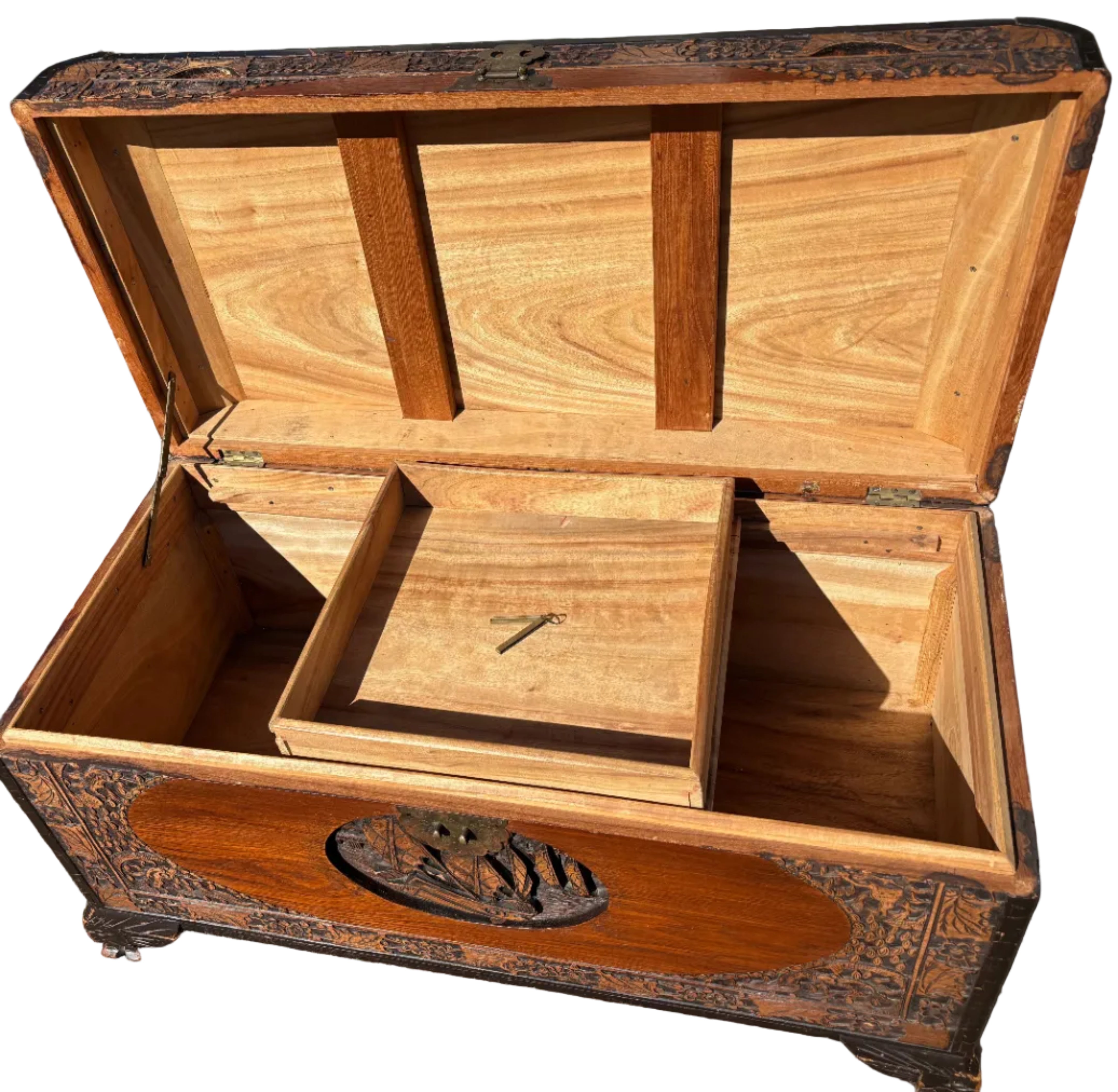 A decorative wooden chest with intricate carvings, open to reveal a spacious interior and a small removable drawer with a key inside.