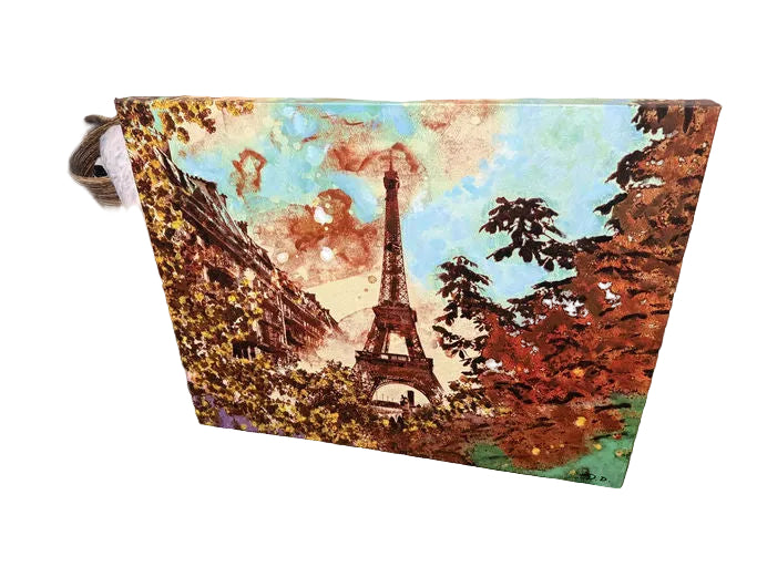 An artistic canvas featuring the Eiffel Tower, surrounded by vibrant autumn foliage and a colorful sky, set against a brick backdrop.