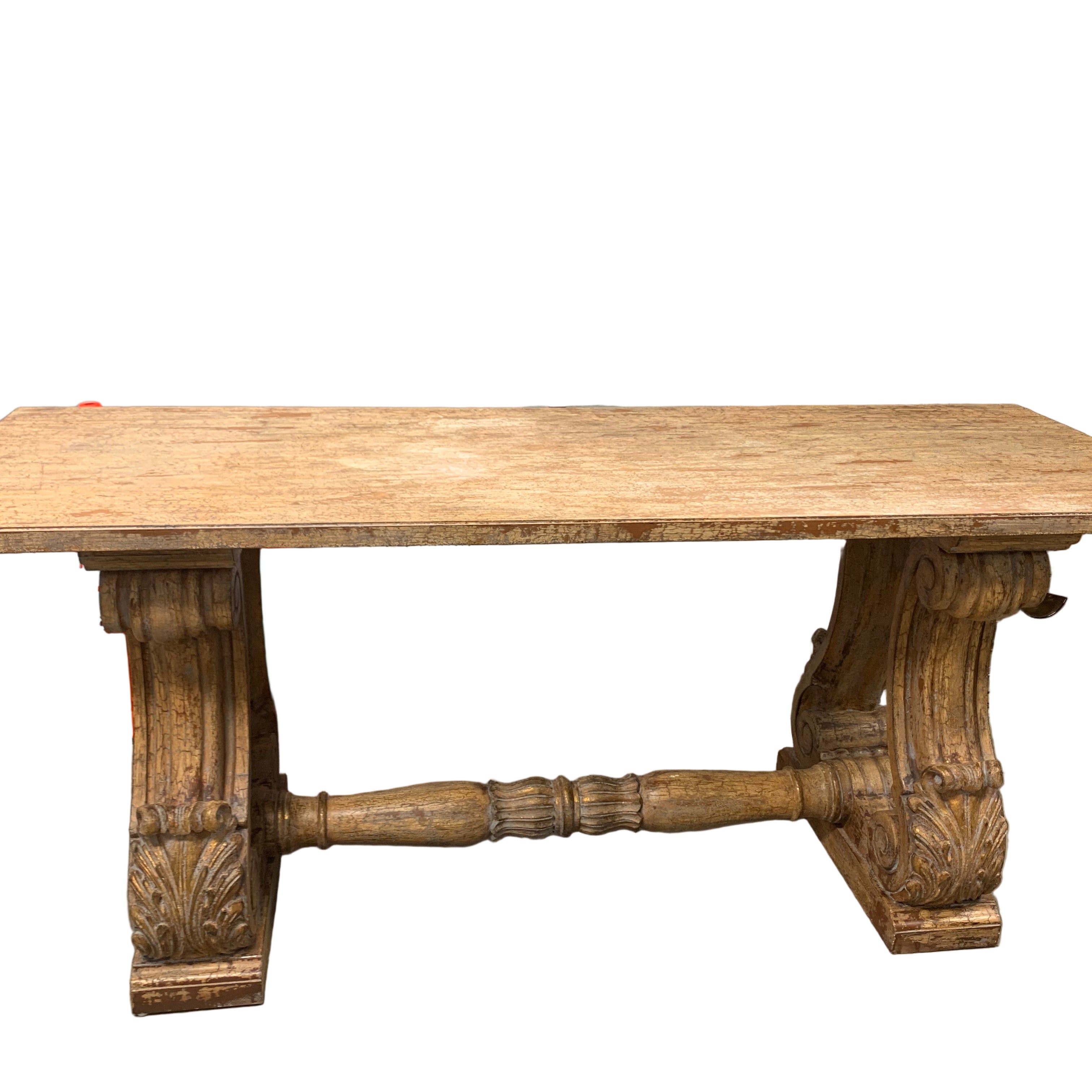 A rustic wooden table with decorative carved legs is centered in a garage. Surrounding items include road cones, a scooter, and cardboard boxes.