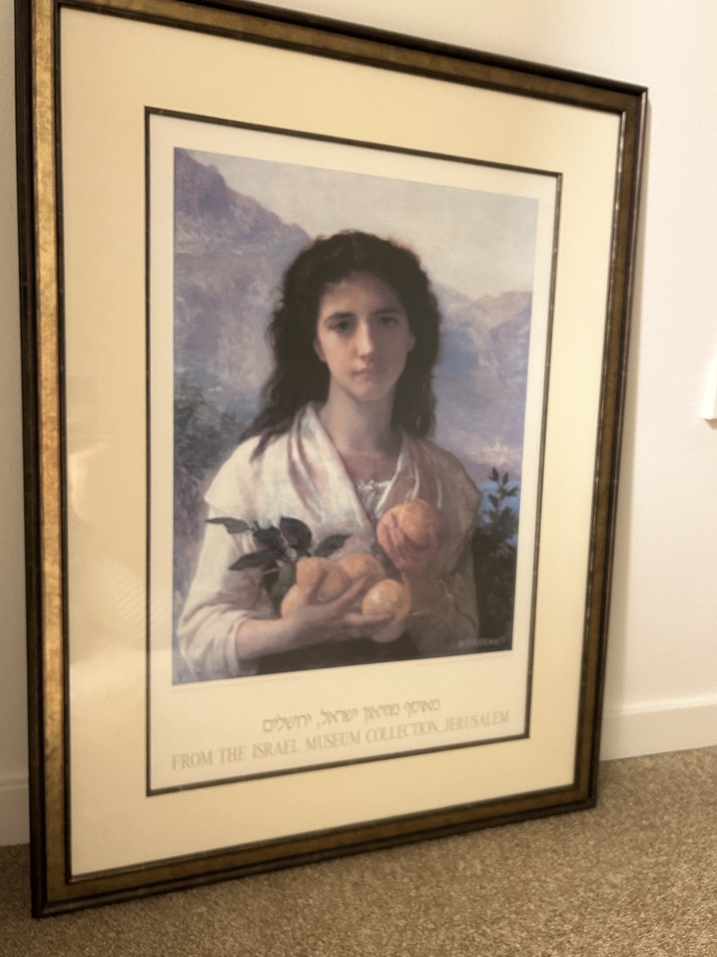 Framed artwork featuring a young woman holding fruit, with mountains in the background. Text below states it is from the Israel Museum Collection.