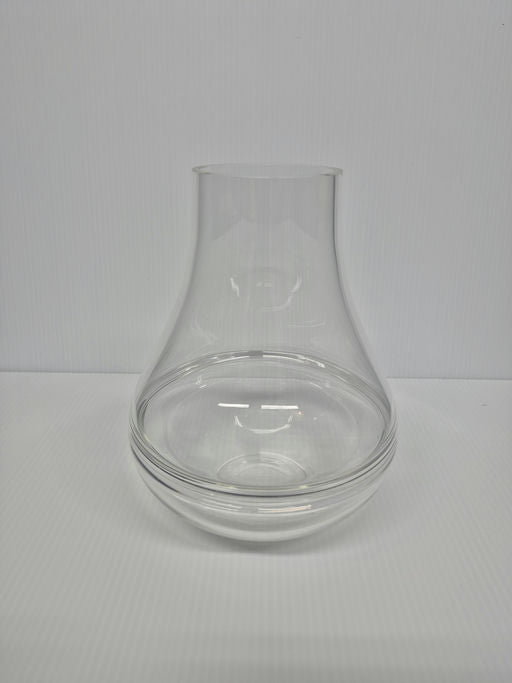 A clear glass vase with a curved shape and a wide opening at the top, resting on a flat surface against a white background.