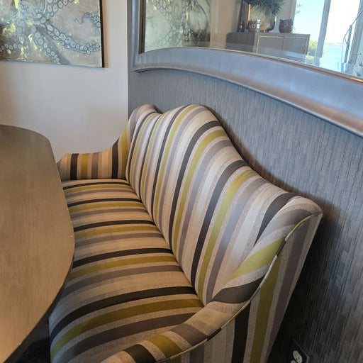 A striped sofa with green, gray, and black patterns sits beside a curved wall, with decorative art featuring octopus imagery in the background.
