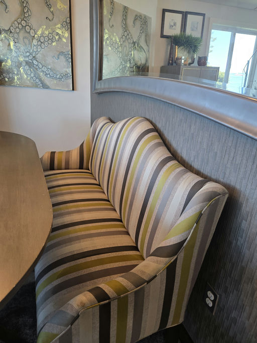 A striped sofa with green, gray, and black patterns sits beside a curved wall, with decorative art featuring octopus imagery in the background.