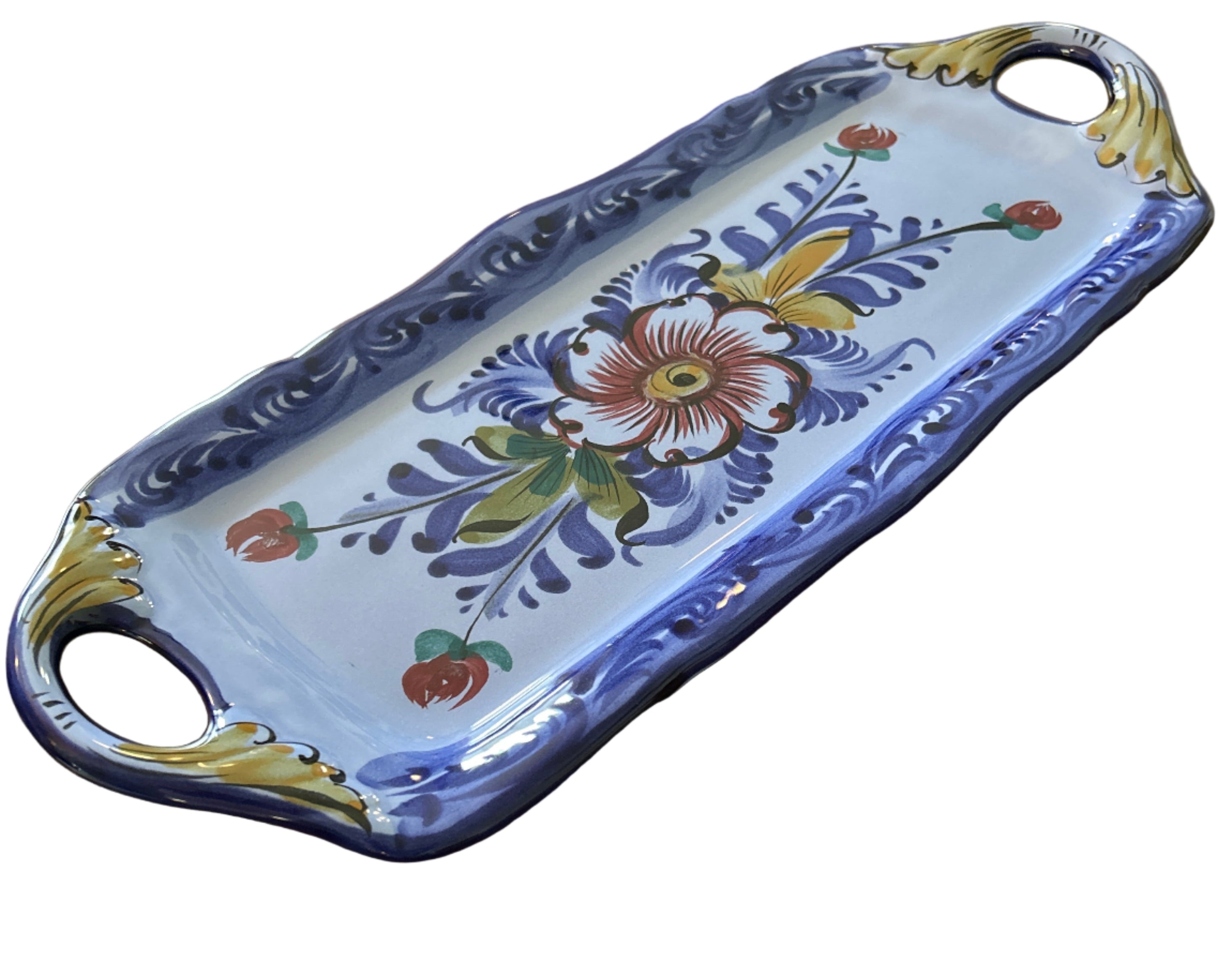 A decorative blue and white serving tray with floral designs and handles rests on a wooden table, showcasing intricate craftsmanship and color.
