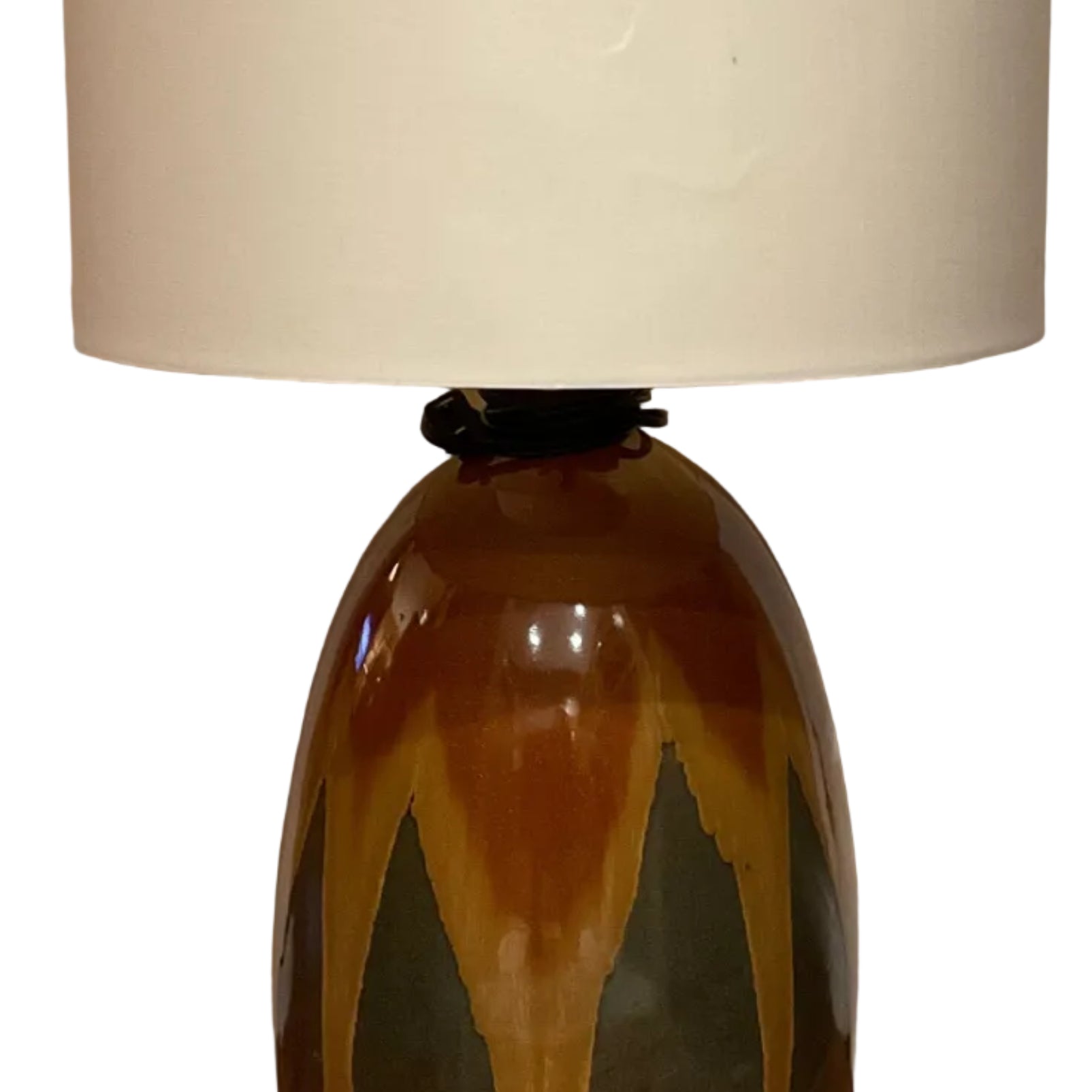 A decorative lamp with a ceramic base featuring earthy colorsβbrown, green, and orangeβtopped with a plain white fabric shade, positioned near a door.