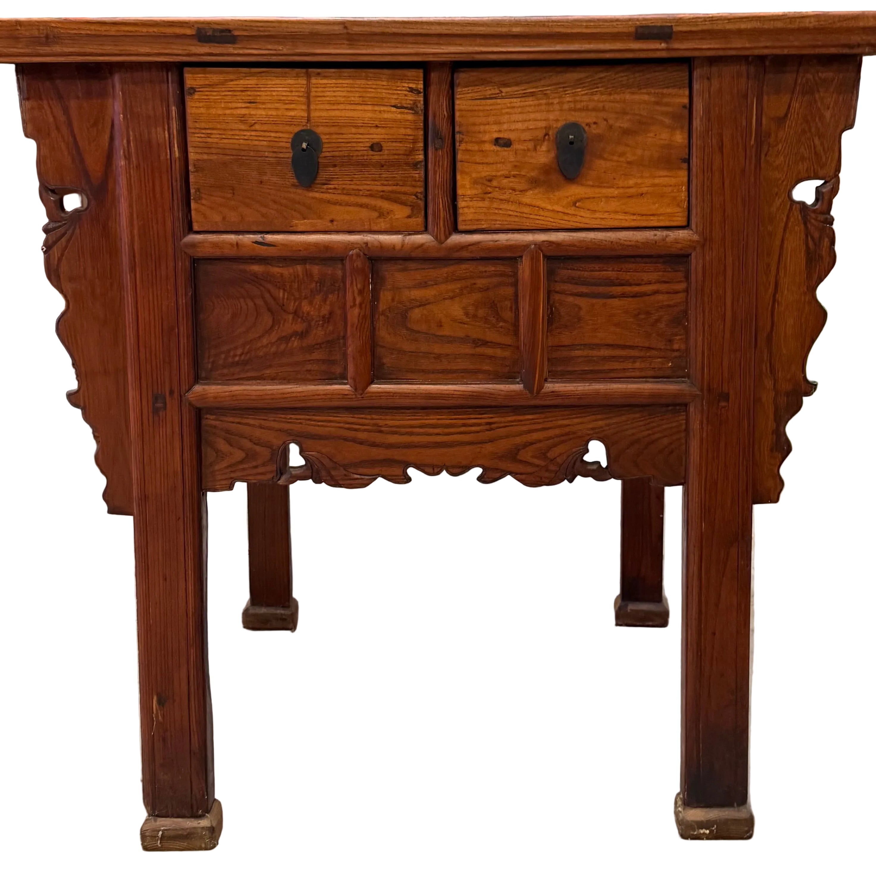 A wooden side table featuring two drawers, intricate carvings on the sides, and a polished finish, set against a cluttered background.