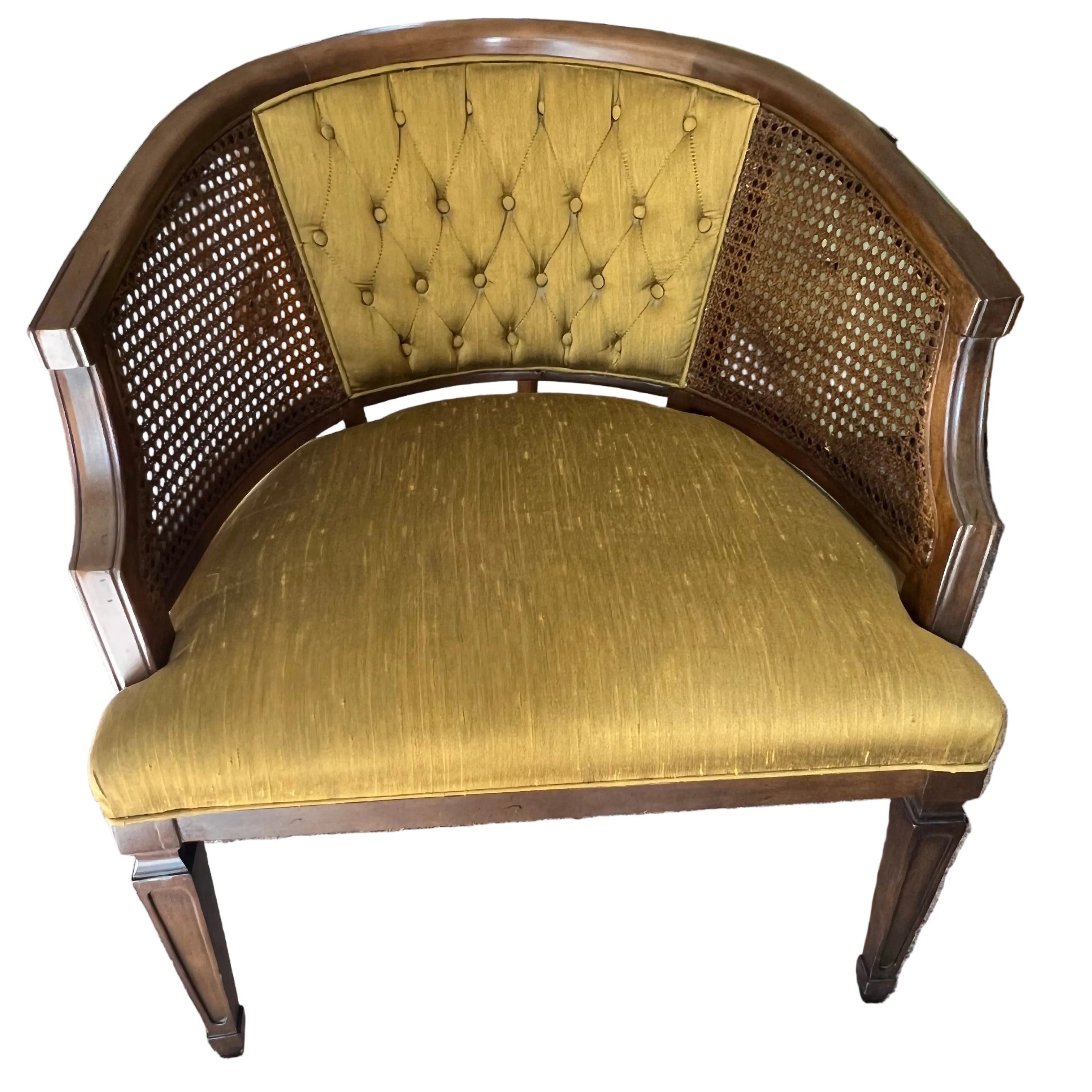 A vintage half-moon chair with a tufted mustard-yellow fabric seat and cane backrest, set on a light carpet, surrounded by household items.