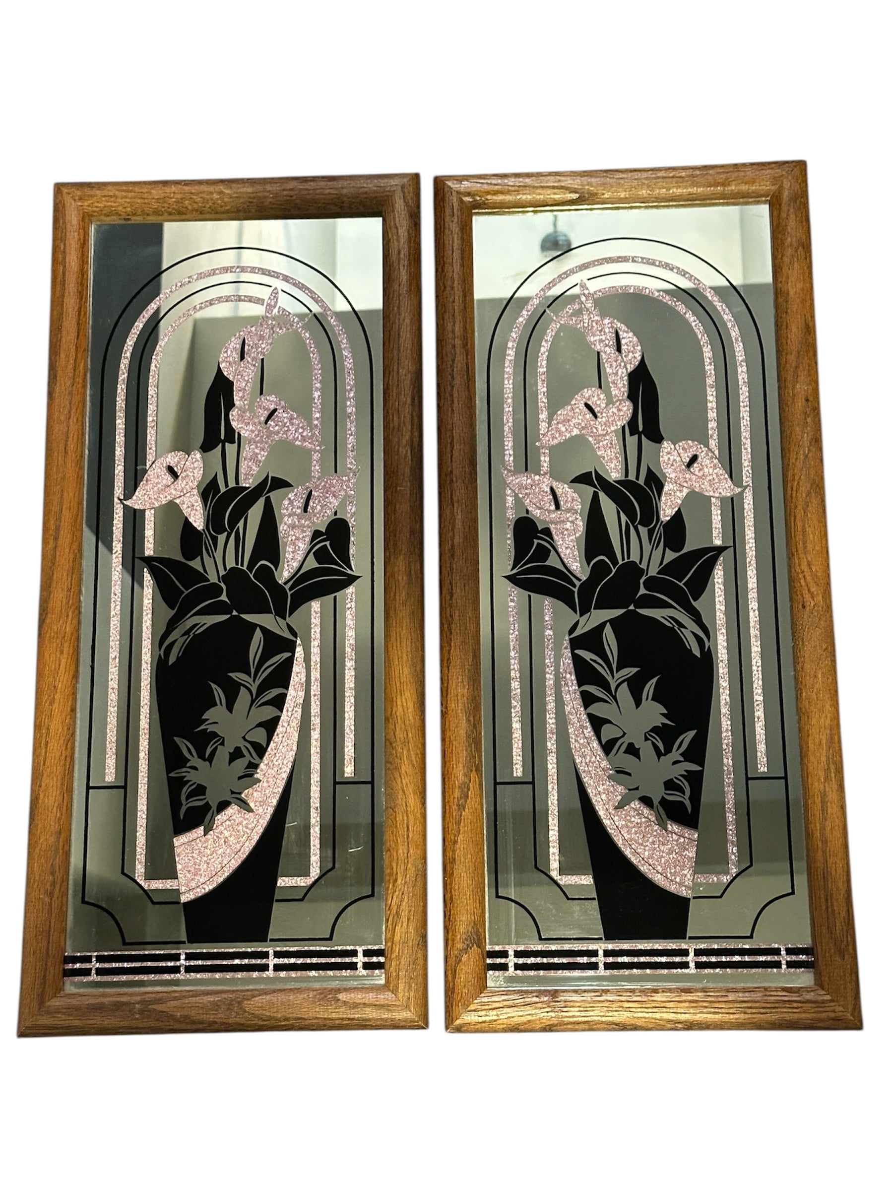 Two decorative wall art pieces featuring black and pink glass designs of flowers in elegant vases, framed in wooden borders. Classic aesthetic.