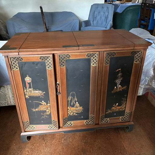 A wooden cabinet with intricate painted panels depicting scenes of boats and landscapes. It features a warm finish and ornate detailing.