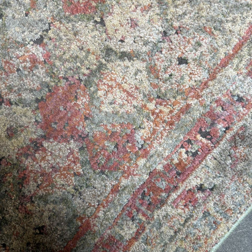 A close-up view of a colorful, patterned rug featuring intricate designs in shades of red, green, and beige with a textured surface.