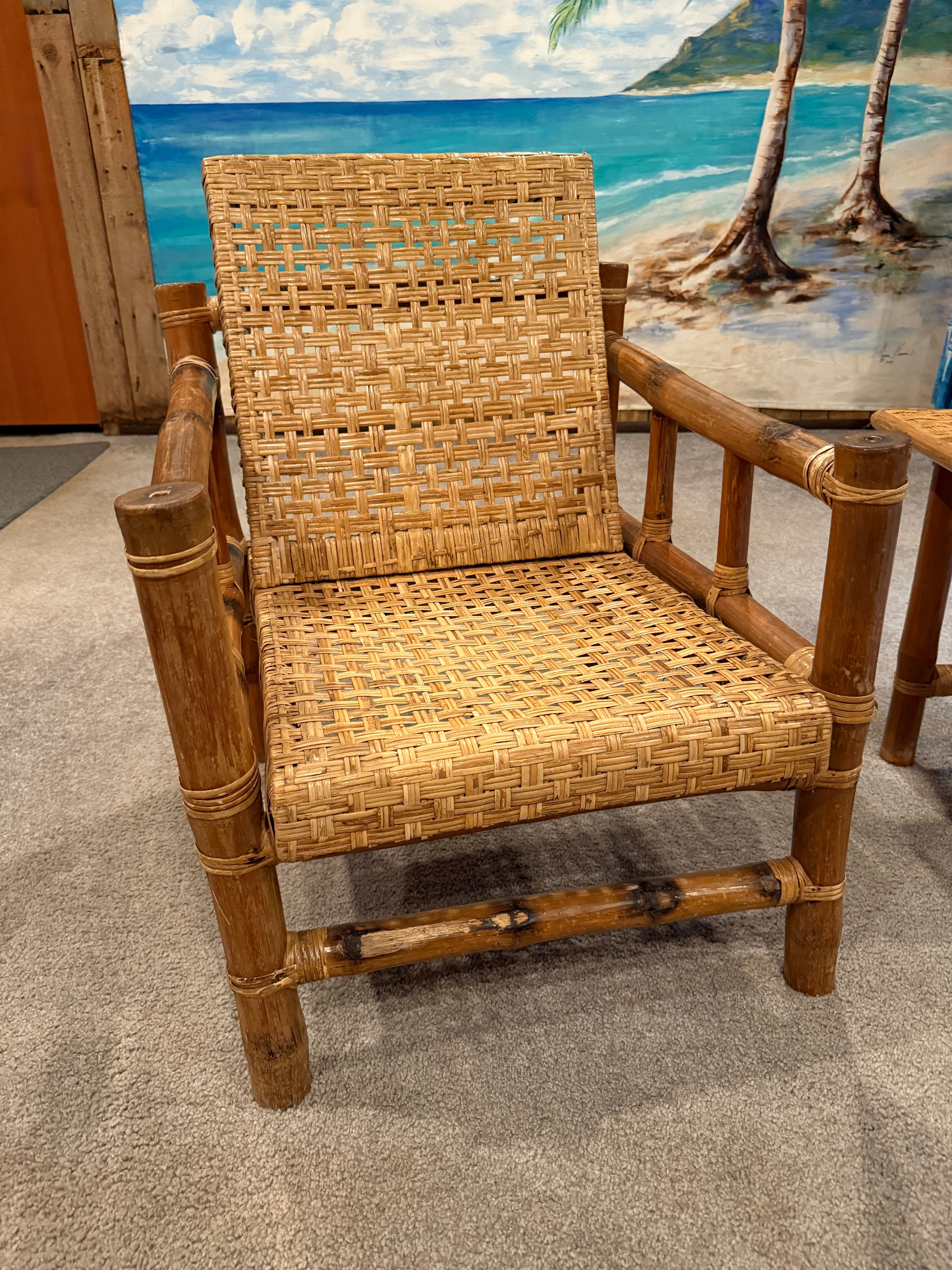 A woven bamboo chair with a natural finish sits on a carpeted floor, set against a colorful beach mural featuring ocean waves and palm trees.