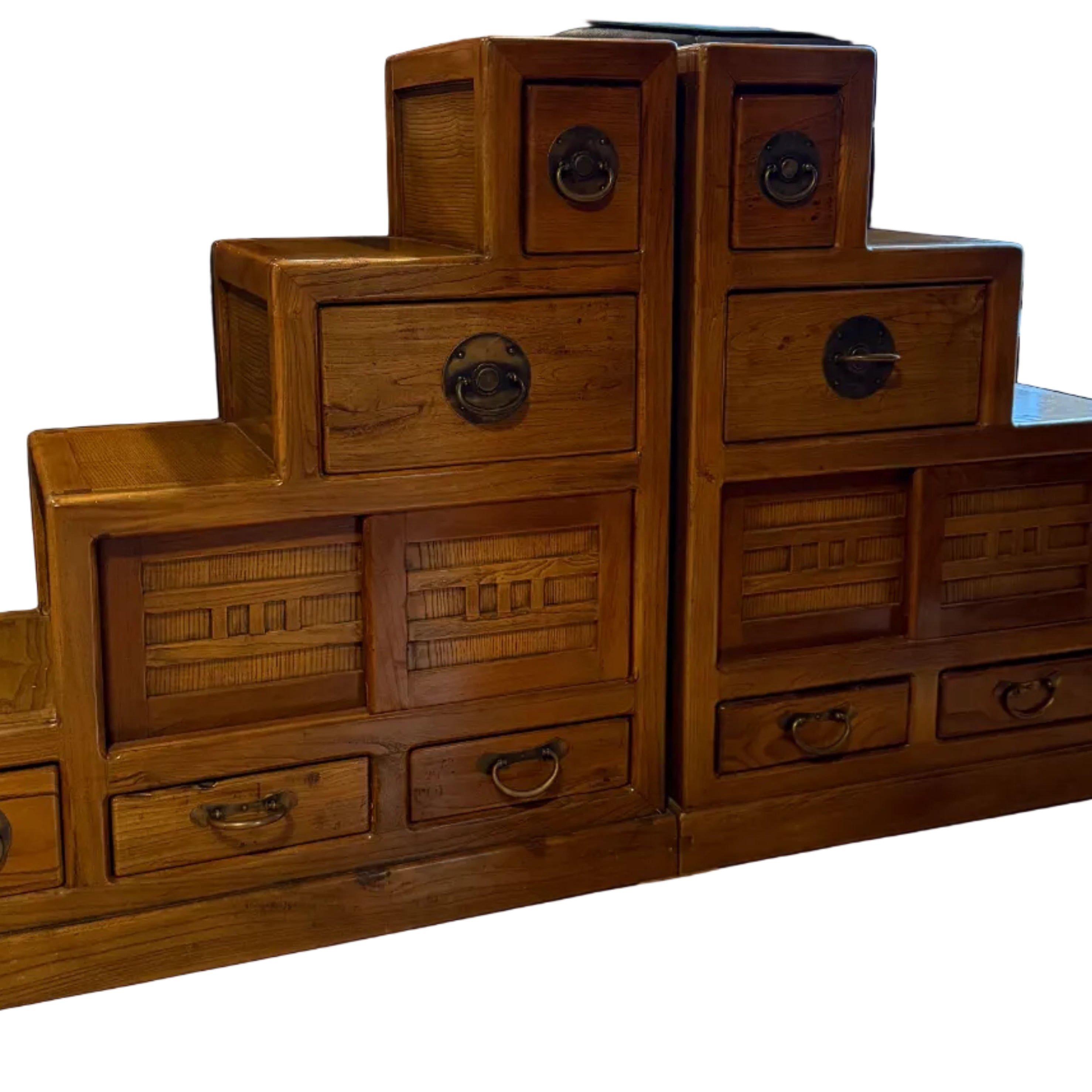 A wooden dresser with several drawers, displaying intricate designs, stands in a spacious room with hardwood floors and large windows.