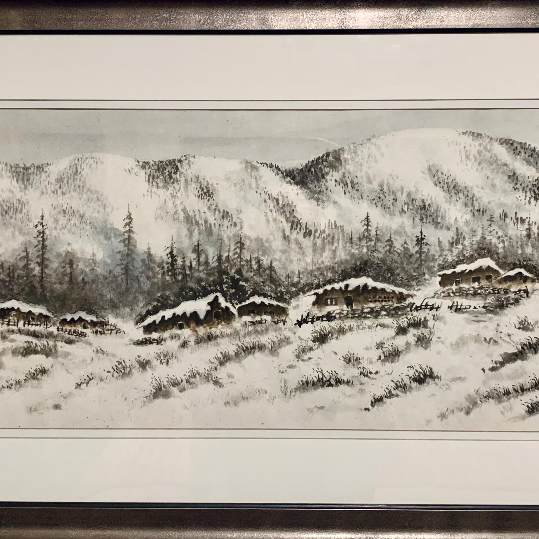 A serene winter landscape featuring snow-covered mountains, pine trees, and rustic cabins nestled in a snowy field, framed elegantly.