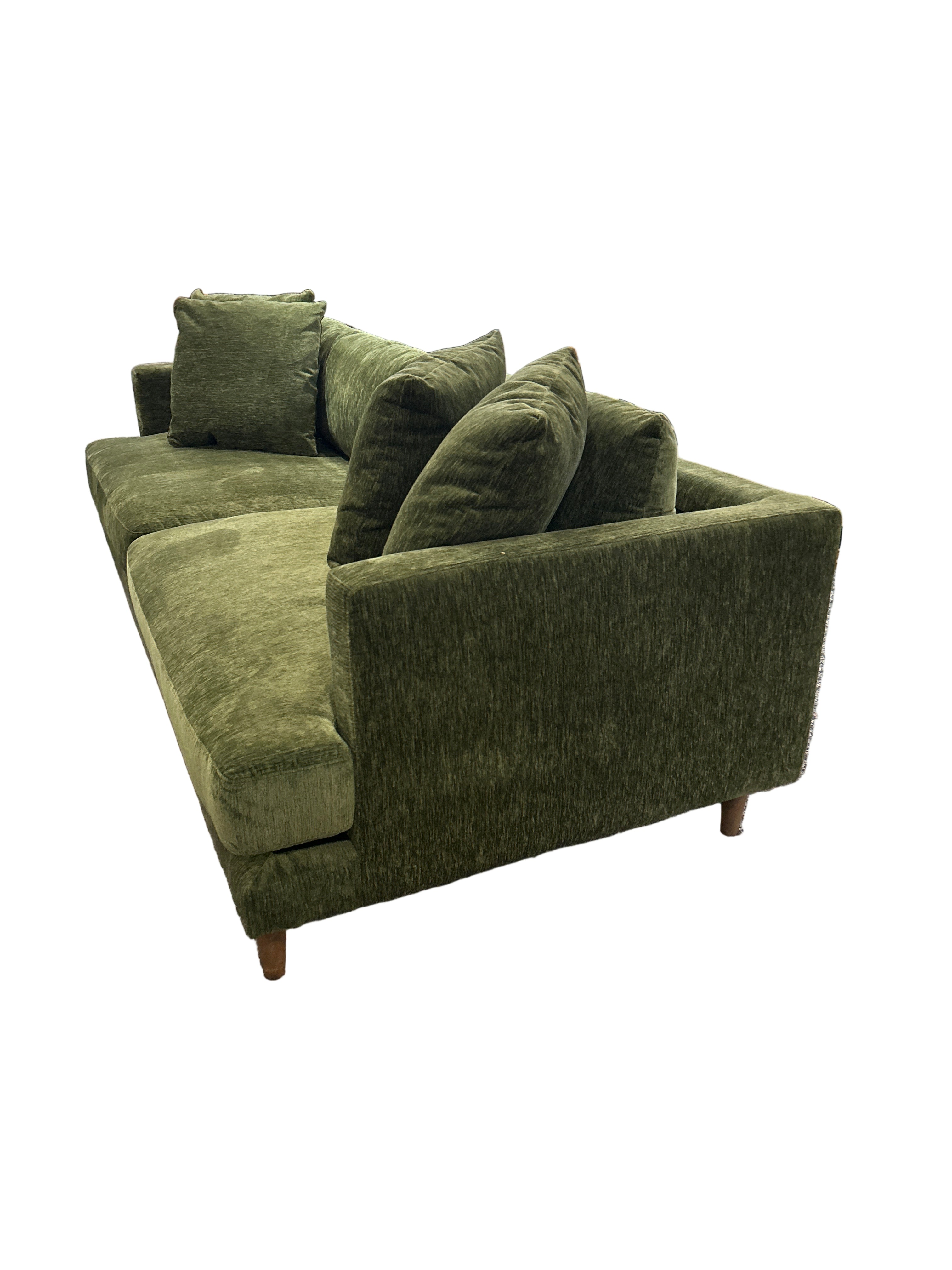 Green upholstered chair in a store setting with shelves and products in the background