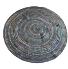A colorful, braided round rug with concentric circles lies on a soft, light gray carpet, adding texture and warmth to the space.