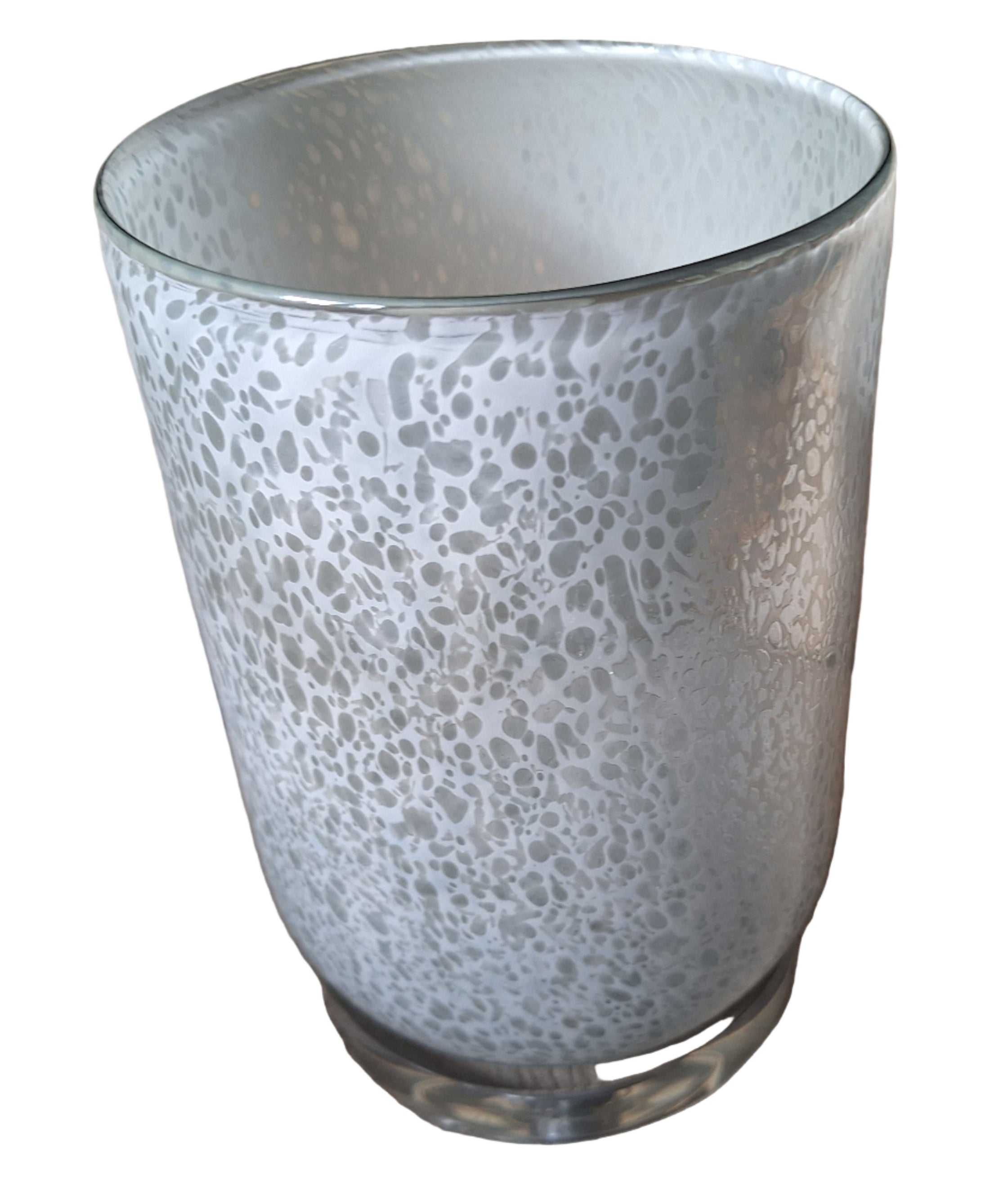 A frosted glass vase with a speckled texture sits on a patterned fabric chair. A clear electrical cord is visible beside it.
