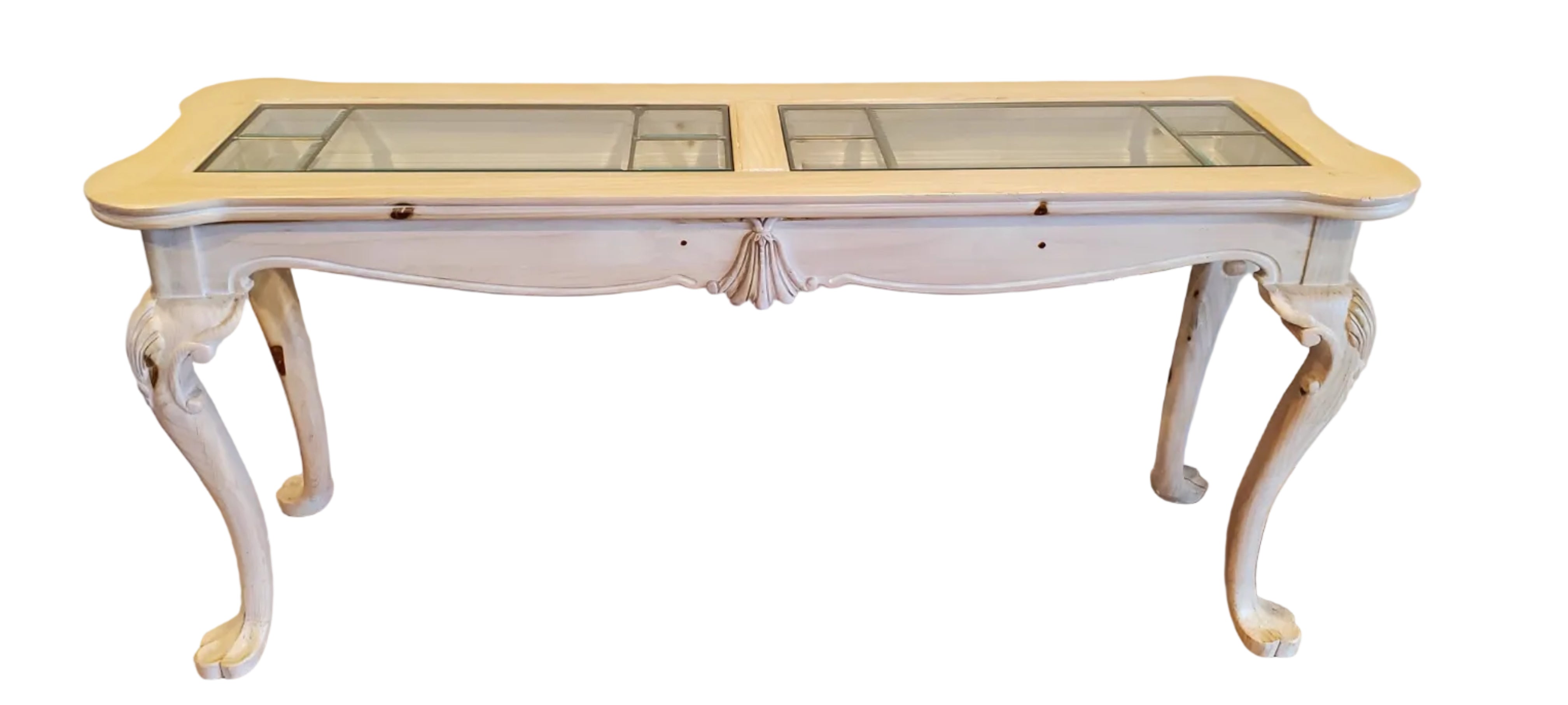 A vintage console table with a light wooden finish and glass panels on top, featuring decorative legs and a smooth surface, against a neutral wall.