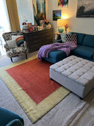 Cozy living room featuring a teal sofa with a purple throw, a patterned armchair, colorful artwork, and a layered area rug. Warm atmosphere.