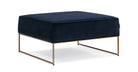 The Bumper is a modern elevated square ottoman in blue velvet fabric. It has a flat upholstered top cushion, gold metal frame with two rectangle side supports. Edge of ottoman has matching piping, sitting comfort is firm.