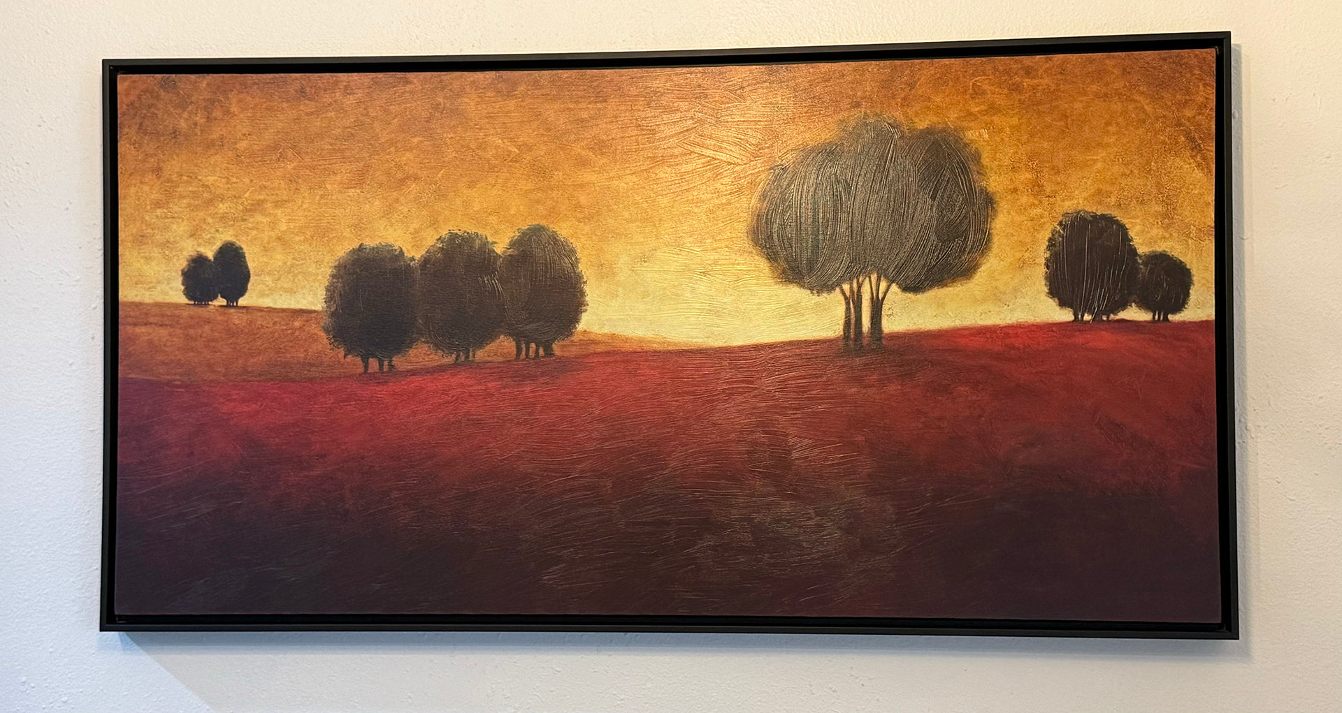 A stylized landscape painting featuring silhouette trees against a warm golden and reddish background, creating a serene, tranquil atmosphere.