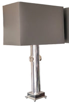 Two modern lamps with rectangular gray shades on a black countertop against a rustic wooden wall. Simple and stylish design for contemporary decor.