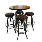 A round dark wood pub-height table with a black metal pedestal base, surrounded by four dark brown upholstered bar stools with black metal frames, photographed in a furniture showroom.