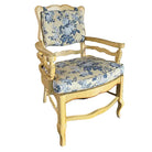 A vintage-style chair with a yellow wooden frame and blue floral upholstery, set against a neutral background with wooden flooring.