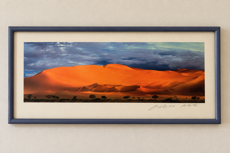 A framed landscape photo depicts vibrant orange sand dunes under a dramatic sky, showcasing the beauty of desert scenery at sunset.
