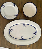 Three ceramic dishes arranged on a wooden table: one large oval platter and two smaller round dishes, all featuring a blue floral design.