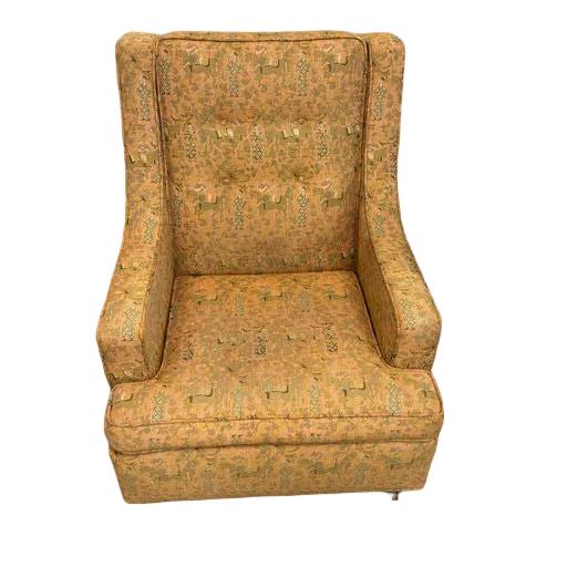A vintage orange upholstered chair with a tufted backrest, located in an office setting. Nearby are shelves with assorted items.