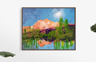 A colorful landscape painting featuring mountains, lush greenery, and a bright blue sky, with reflections in a serene water surface.