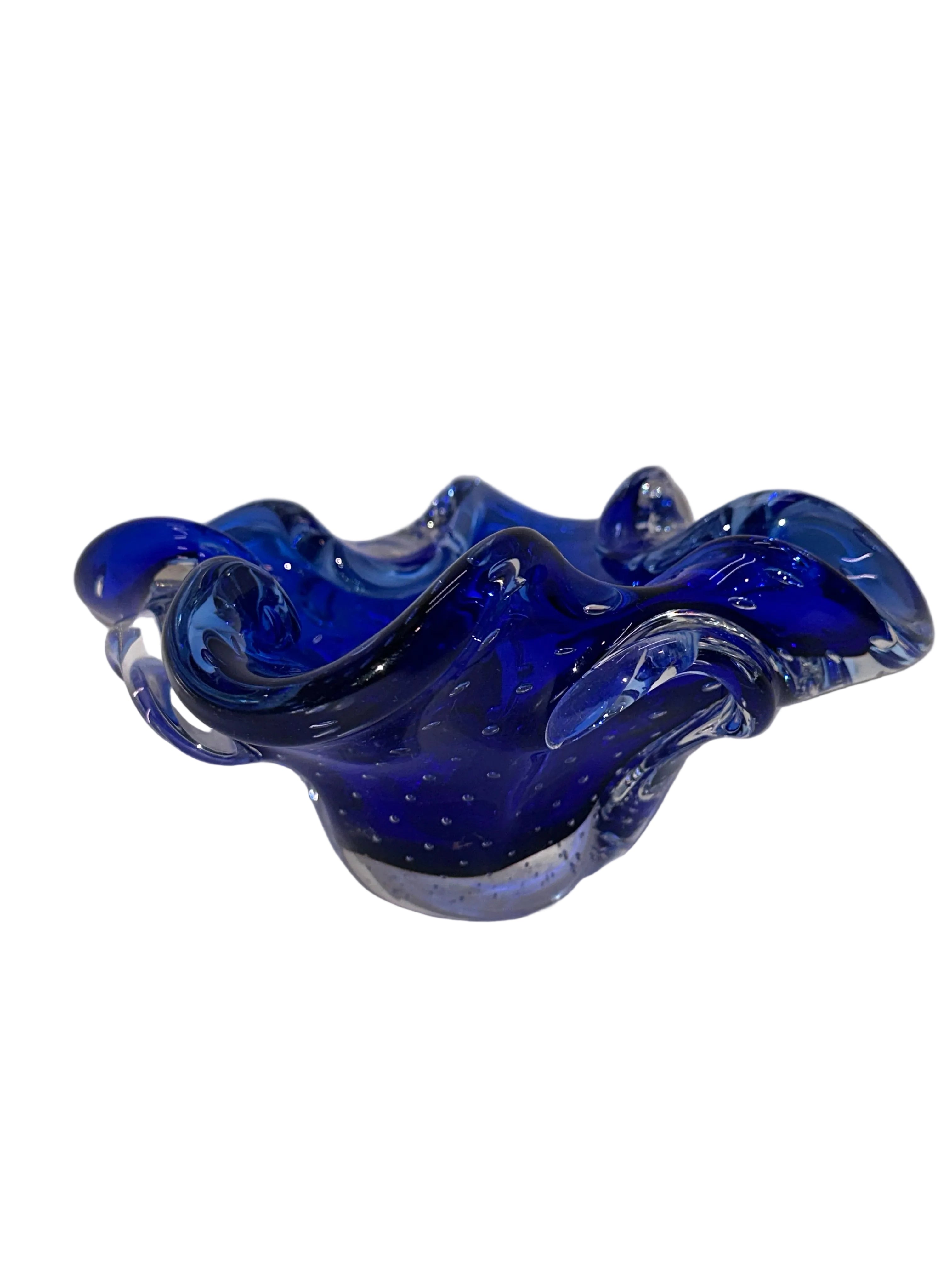 A decorative, wavy glass bowl in deep blue, featuring bubbles and a glossy finish. It rests on a white background, showcasing its intricate design.