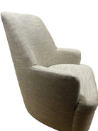 A light gray, textured armchair is positioned at an angle. Behind it is a closed door painted in muted tones, adding a cozy feel to the room.