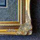 Close-up of the bottom right corner of the ornate golden frame, highlighting the intricate carvings and decorative elements.