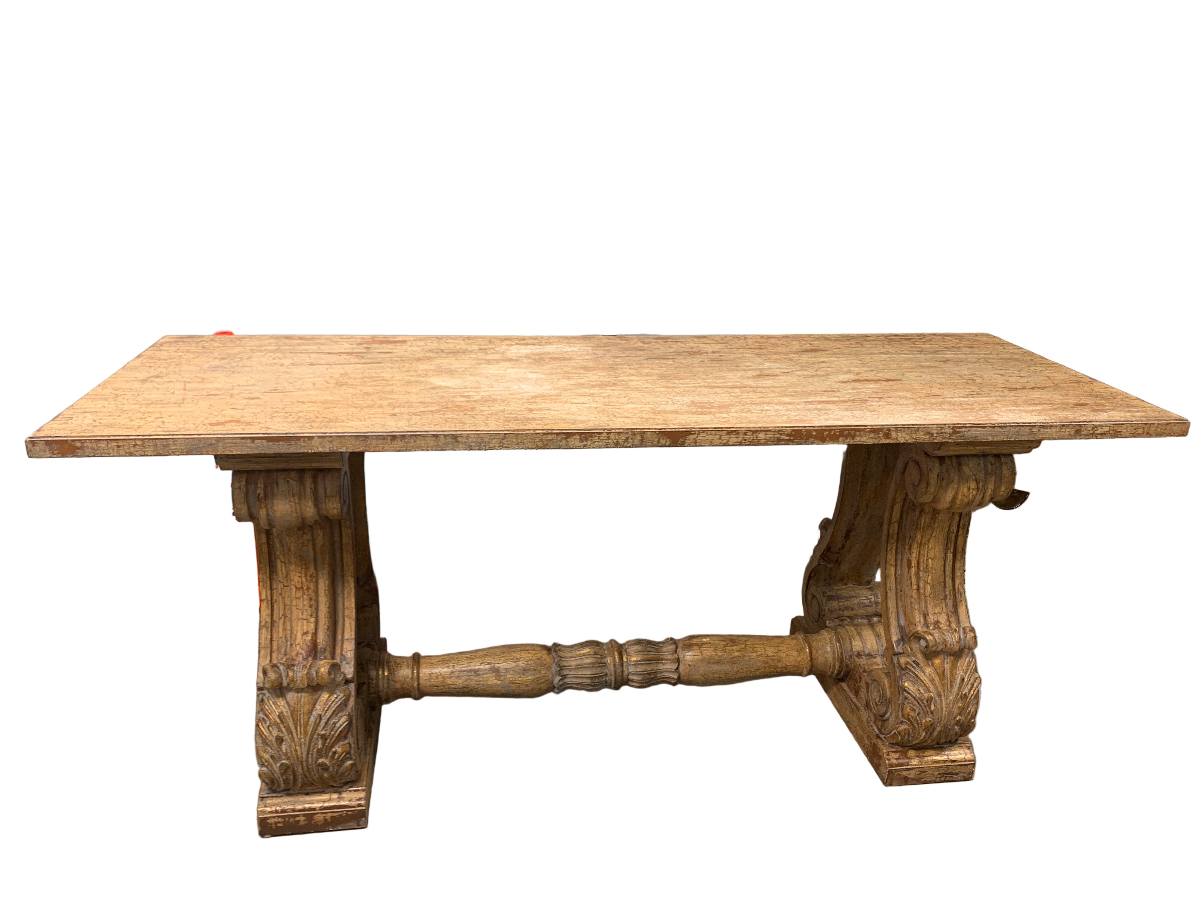 A rustic wooden table with decorative carved legs is centered in a garage. Surrounding items include road cones, a scooter, and cardboard boxes.