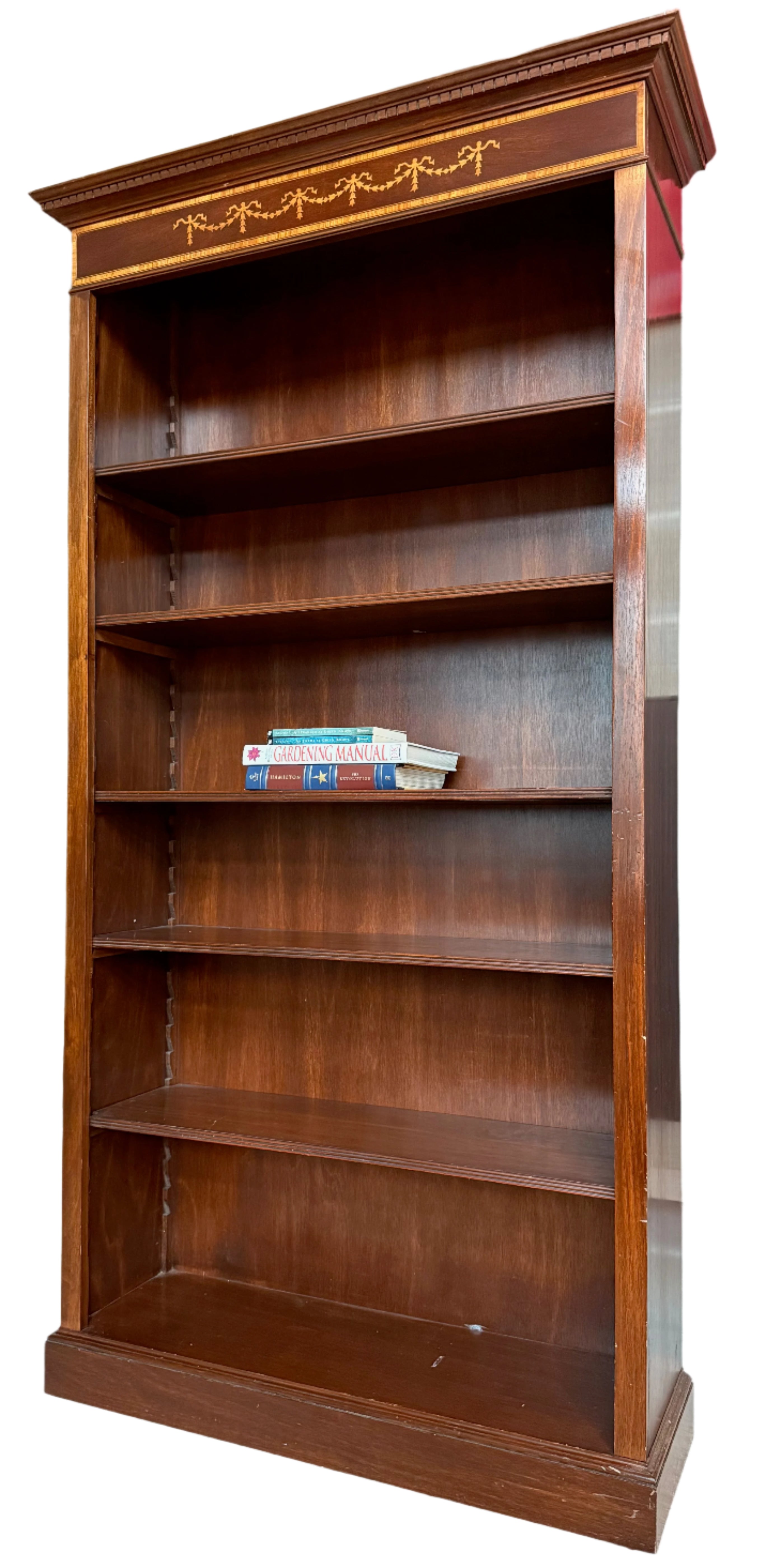 A wooden bookshelf with a rich finish showcases three shelves, two of which are empty. A few books are neatly arranged on the lower shelf.