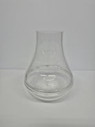 A clear glass vase with a curved shape and a wide opening at the top, resting on a flat surface against a white background.