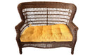 A wicker loveseat with a bright yellow cushion sits on carpet, near a dining table. A red backpack and a green bag are visible in the background.