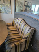 A striped sofa with green, gray, and black patterns sits beside a curved wall, with decorative art featuring octopus imagery in the background.