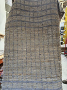 A textured woven rug displayed vertically, featuring a grid pattern in shades of brown and gray, highlighting its natural fibers and craftsmanship.